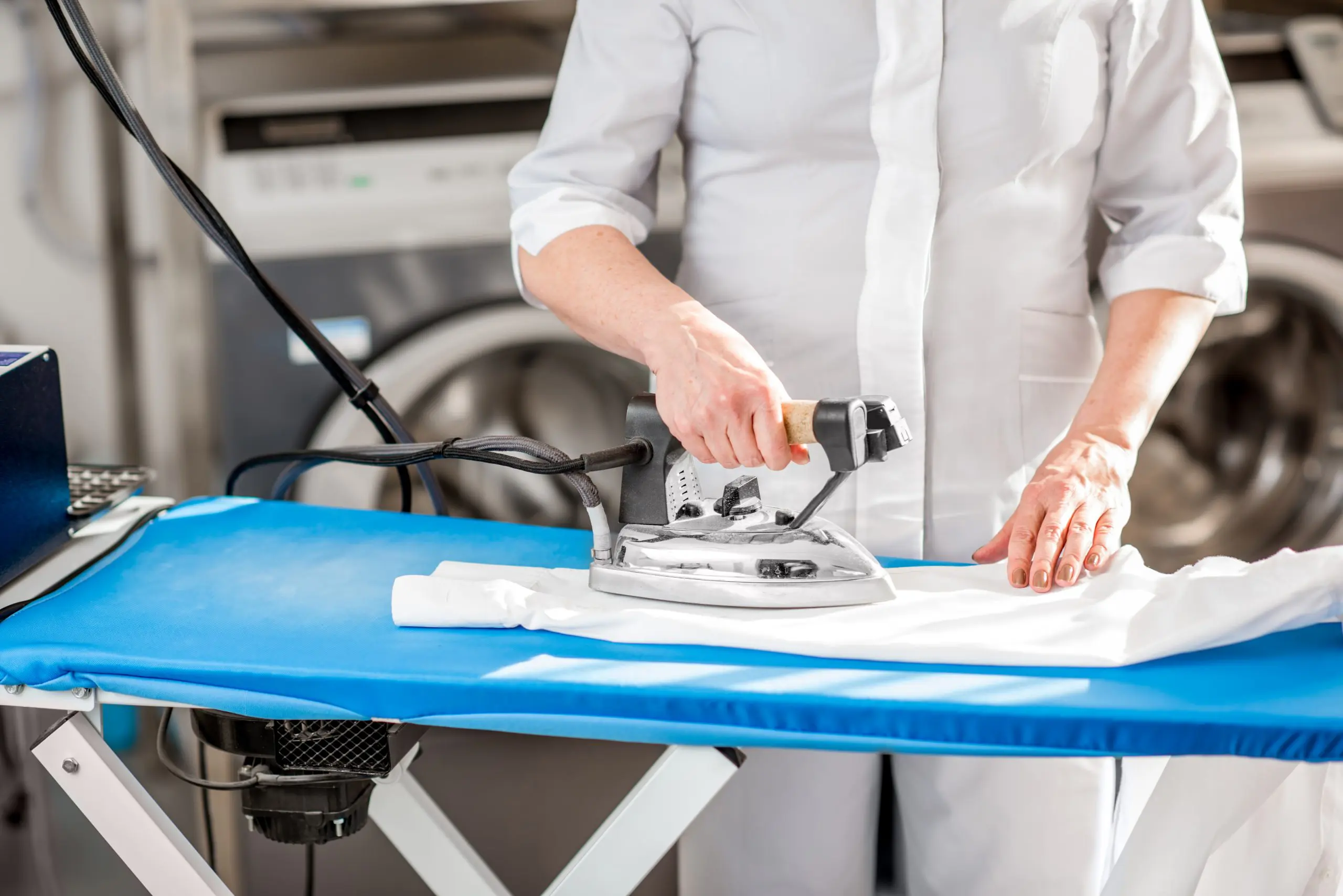 A woman ironing a shirt in a laundry room.