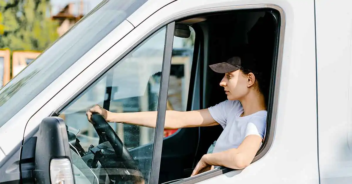 A woman sitting in the driver's seat of a white van.